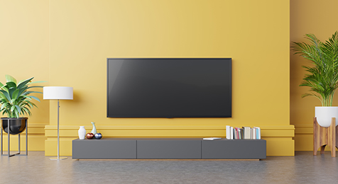 TV on cabinet in modern living room with lamp,table,flower and plant on yellow wall background,3d rendering